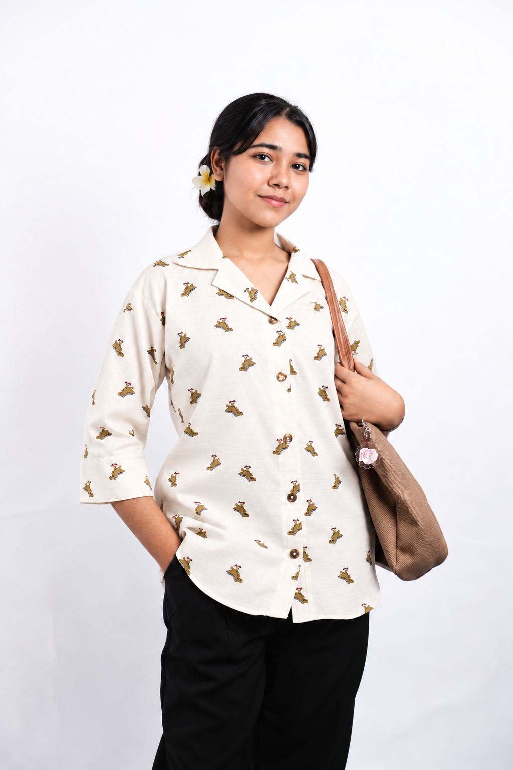 Dino Daze ivory dinosaur-print shirt styled with black trousers and a shoulder bag, showing the relaxed silhouette and curved hem.