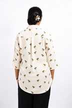 Back view of Dino Daze ivory dinosaur-print ladies shirt, showing the back yoke, centre pleat, three-quarter sleeves and curved hem.