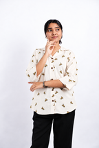 Dino Daze ivory dinosaur-print ladies shirt, front studio pose showing Cuban collar, brown buttons, relaxed fit and curved hem.