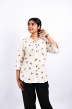 Dino Daze dinosaur-print shirt in a three-quarter studio view, showing its open Cuban collar, three-quarter sleeves and curved hem.